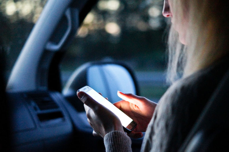 Close-up of woman using mobile phone in car