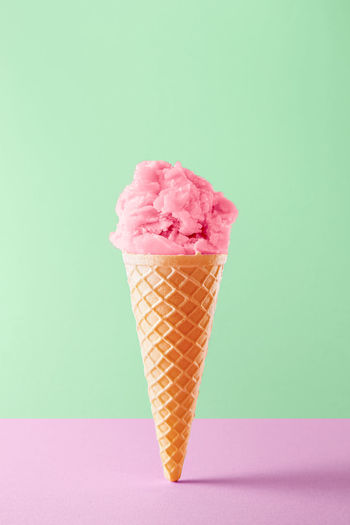 Pink ice cream cone against green background