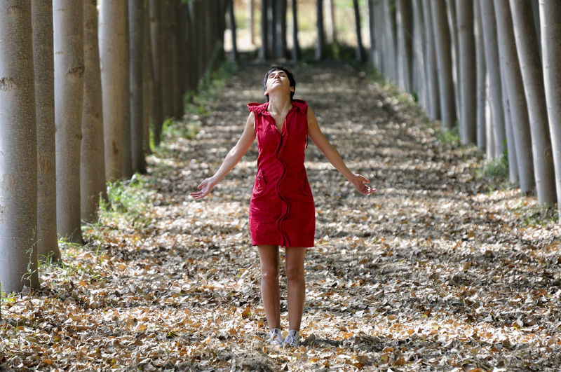 Full length of young woman standing on footpath amidst trees
