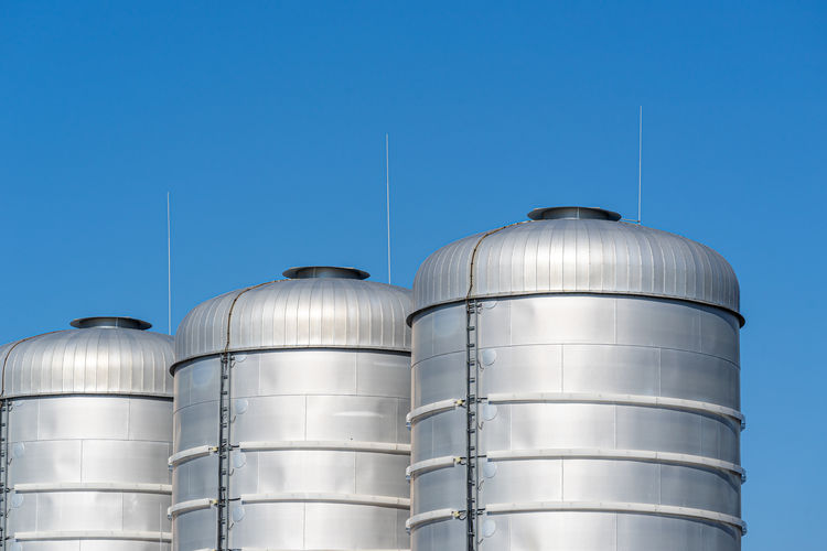 Low angle view of storage tanks against blue sky