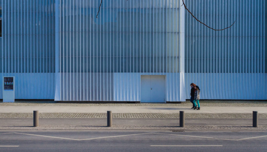 Side view of man walking on footpath against building