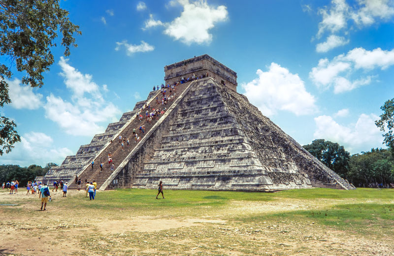 People at chichen itza against sky