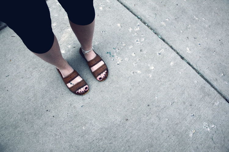 Low section of woman with black nail polish standing on pathway