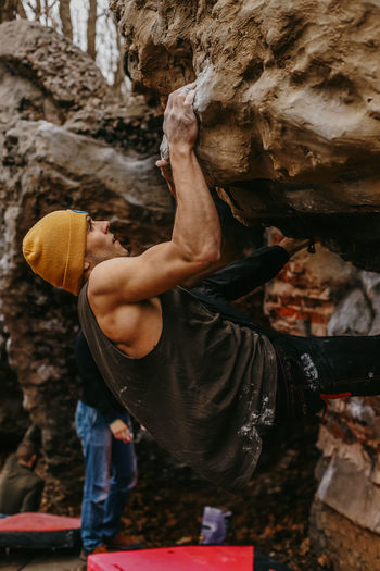Side view of determined man climbing rocky mountain