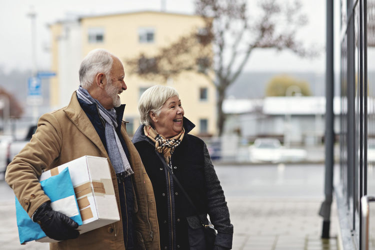 Smiling senior couple with package in city during winter