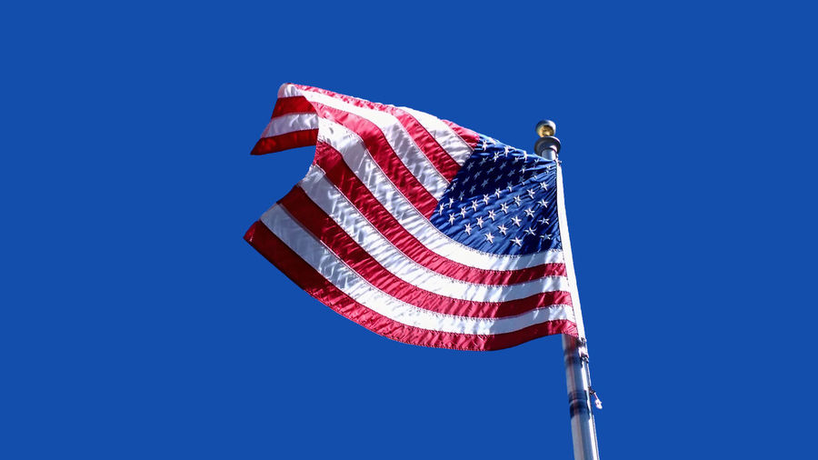 American flag unfurled and waving against a deep blue sky