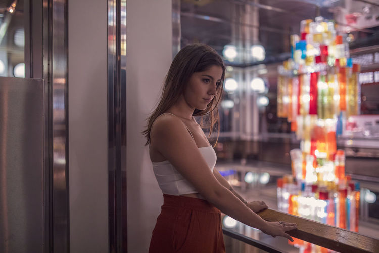 Young woman looking away while standing in shopping mall