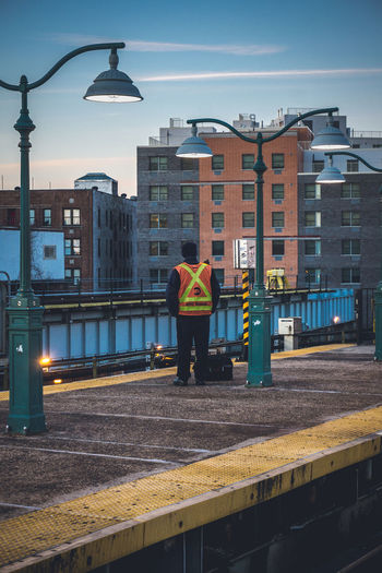 Rear view of worker standing on pier against buildings