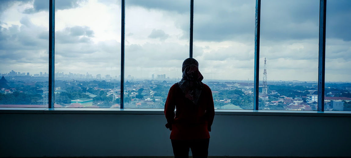 Rear view of woman standing by window