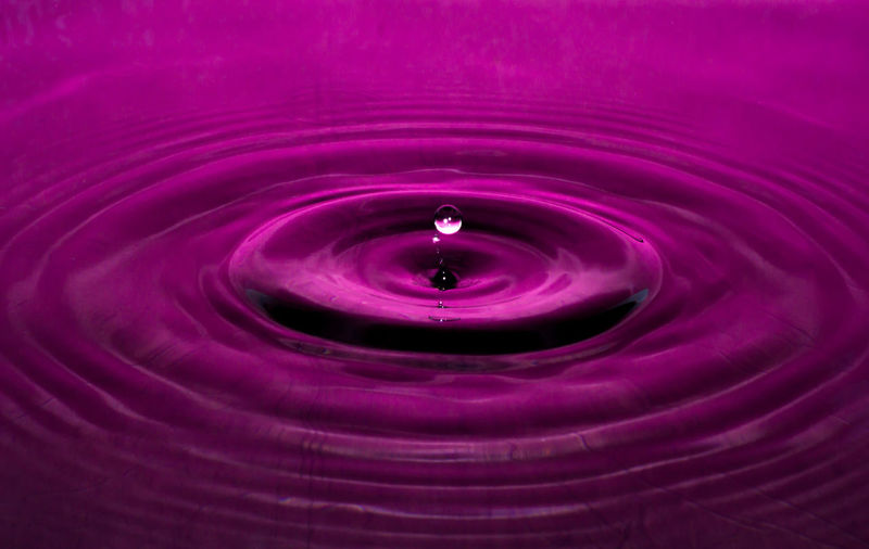 Close-up of drop splashing in pink water
