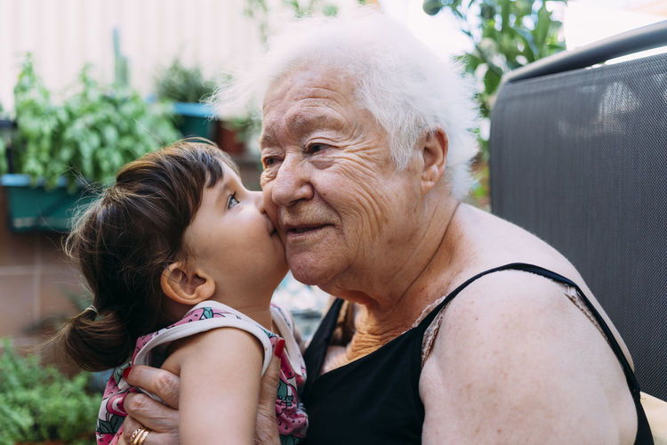Baby girl kissing her grandmother on terrace