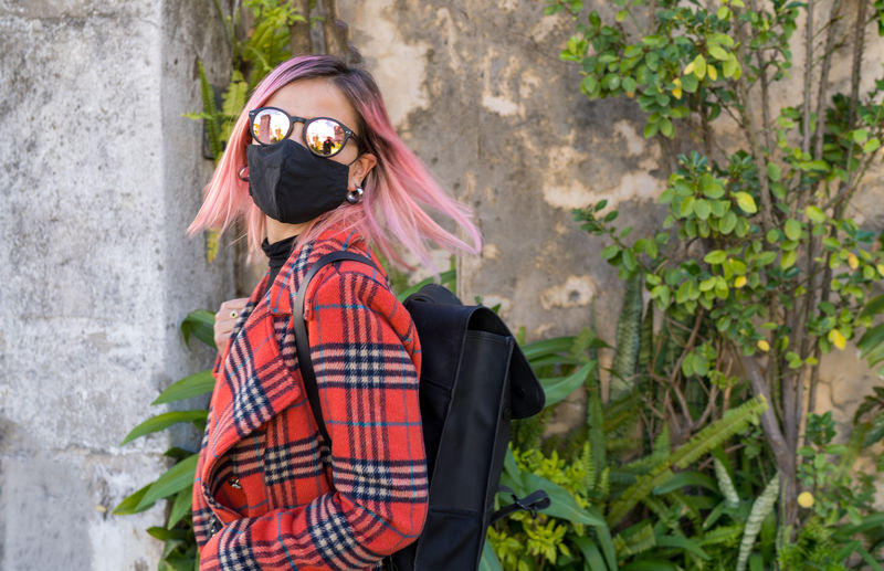 Traveler woman with mask in protection to the pandemic observes
the exotic travel vegetation
