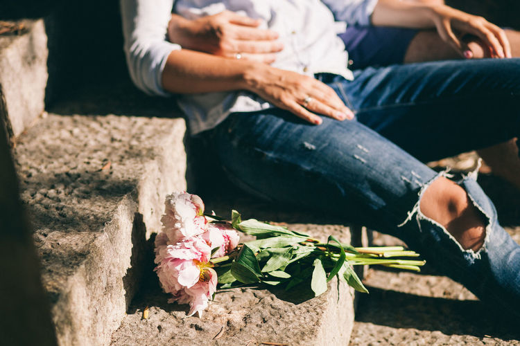 Midsection of couple with bouquet sitting on steps