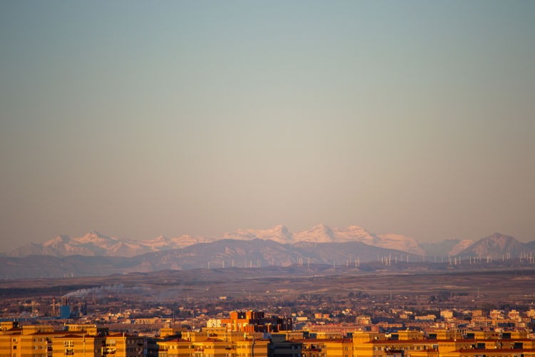 Aerial view of townscape and mountains against clear sky