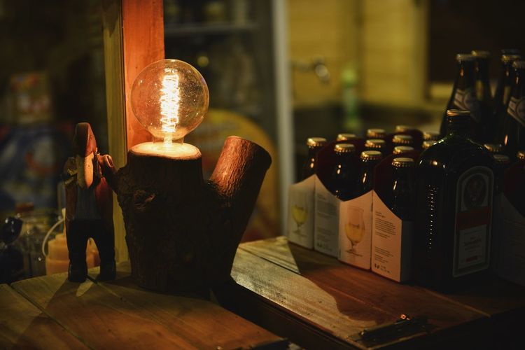 Close-up of illuminated electric bulb on wood at table