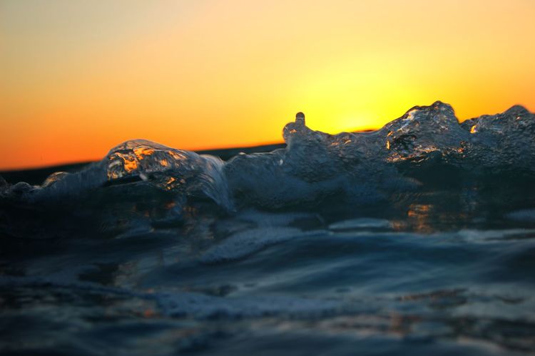 Surface level of frozen sea against sky during sunset