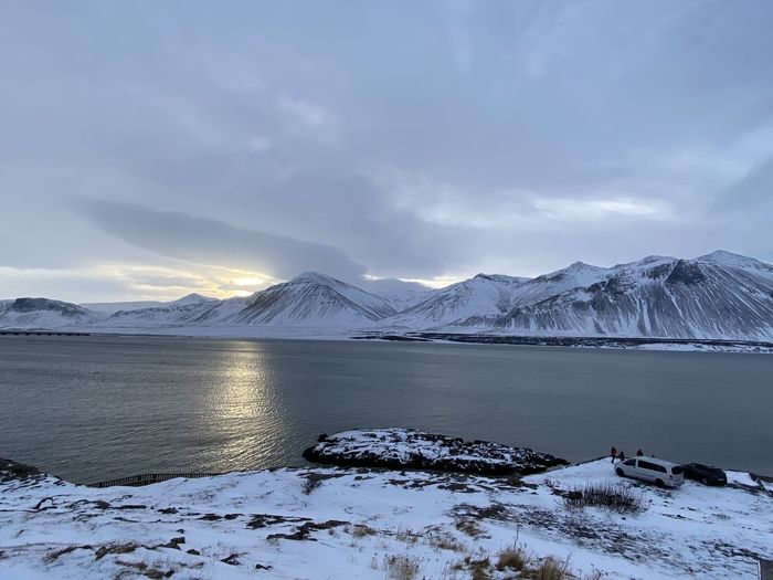 Scenic view of frozen lake by snowcapped mountains against sky