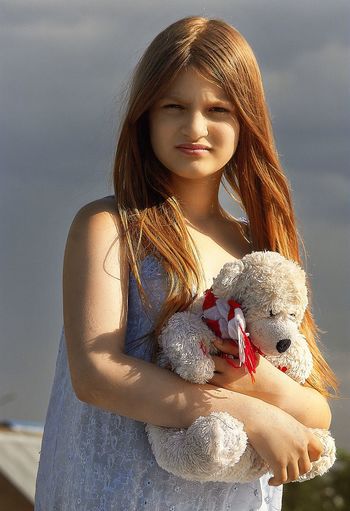 Close-up of girl looking at camera against sky