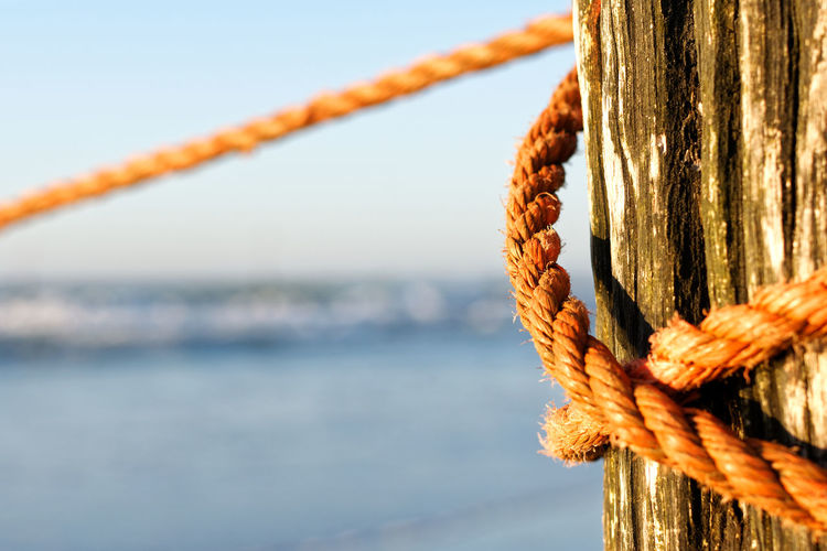 Close-up of rope tied on metal against sea