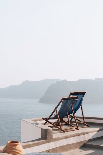 Chair on beach against clear sky