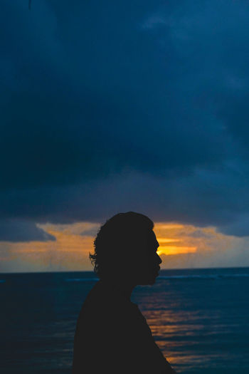 Silhouette man by sea against sky during sunset