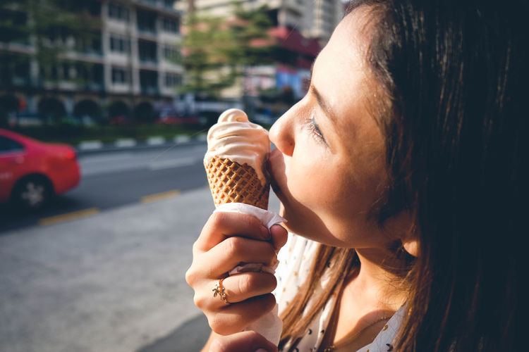 Woman eating ice cream cone in city