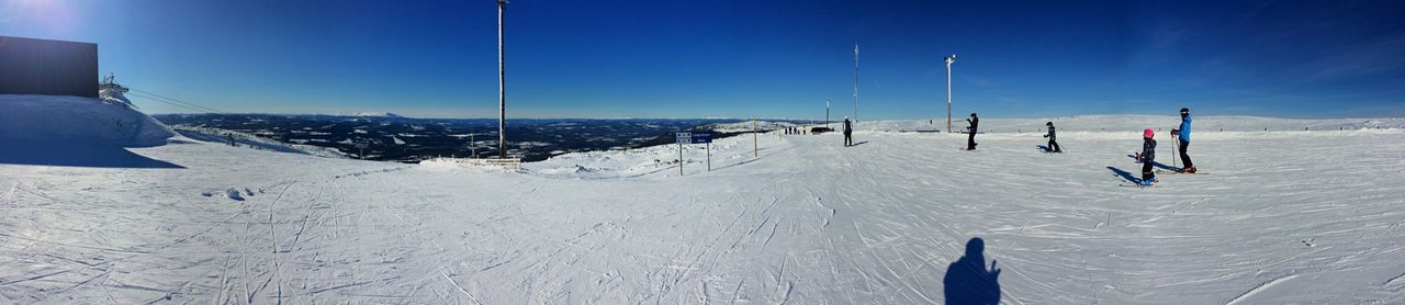 Panoramic view of people skiing on snow covered landscape
