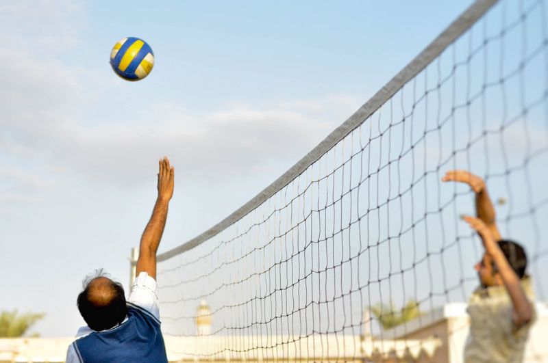 Men playing volleyball against sky