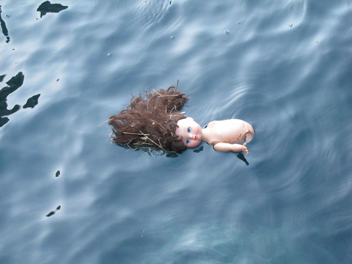 High angle view of broken doll floating on water