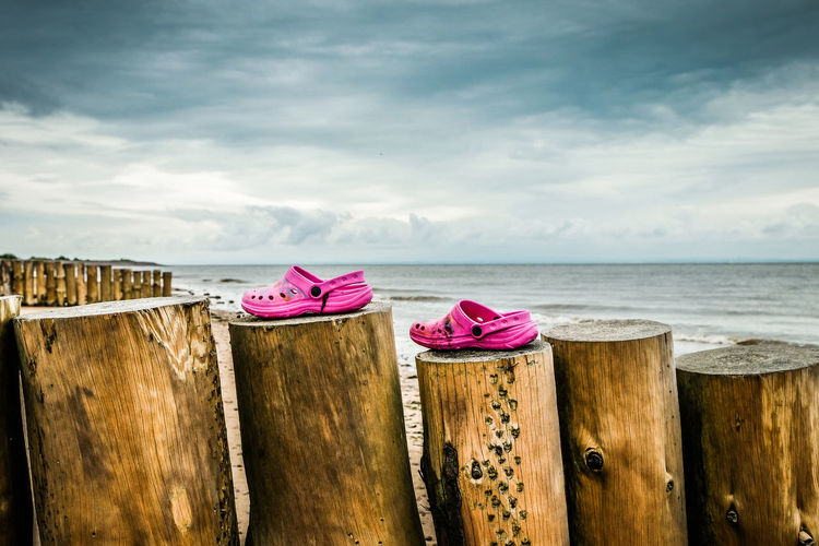 Pink shoes on a seaside breaker with sea and clouds in the background 
