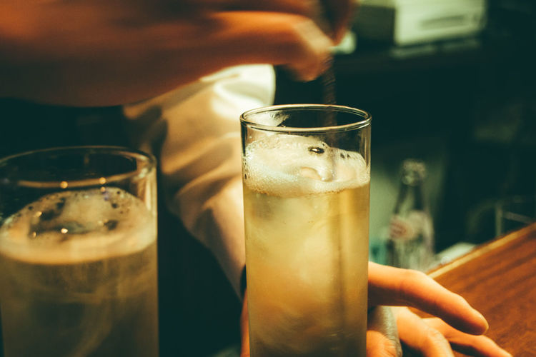 Cropped hands of bartender stirring alcohol in glass on bar counter