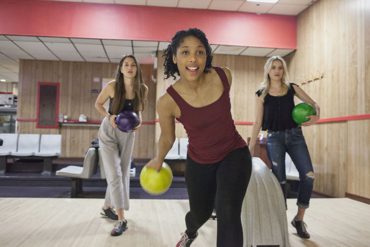 A young woman bowling with friends.