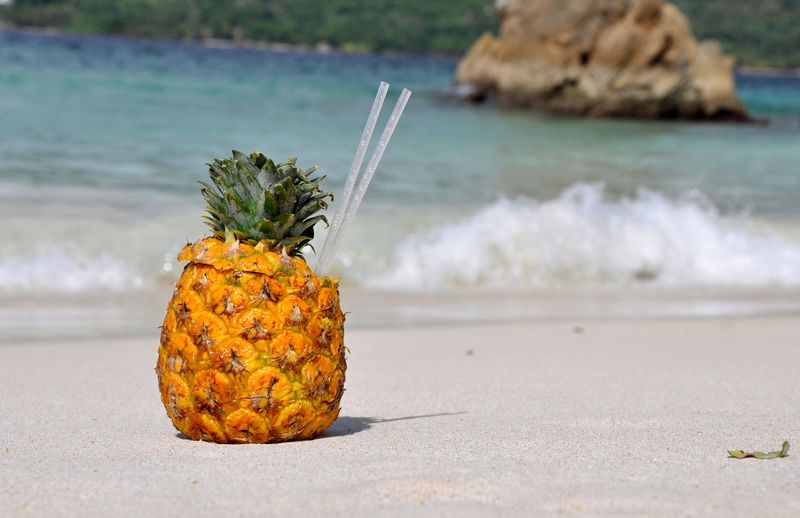 Drinking straws in pineapple at beach