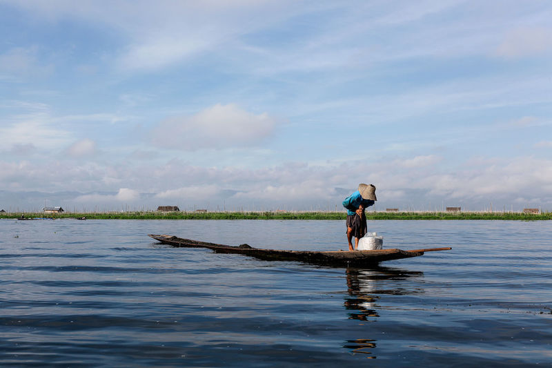 Man traveling in boat on lake against sky