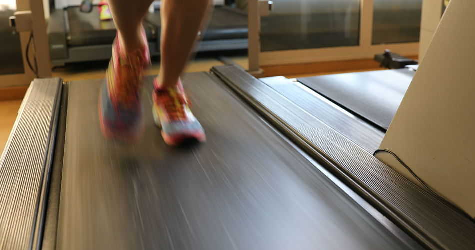 Low section of woman running on treadmill in gym