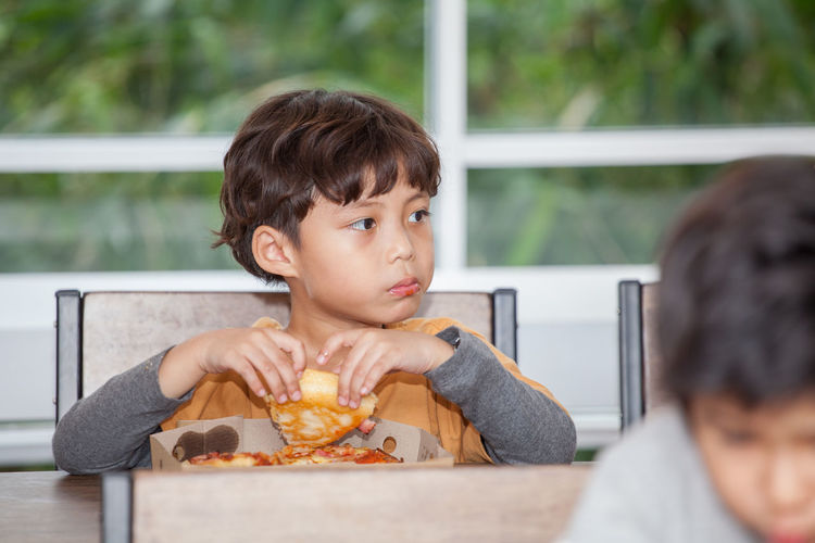 Boy eating from lunch box in classroom at school