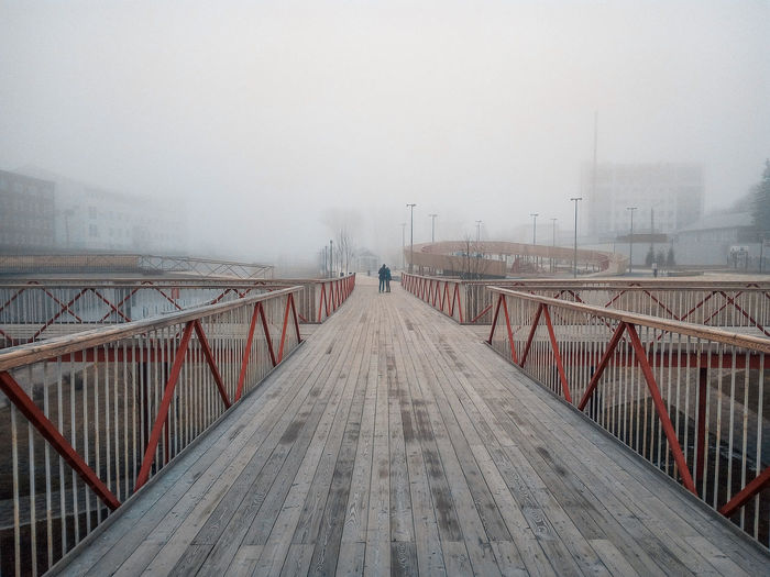 Footbridge in city against sky