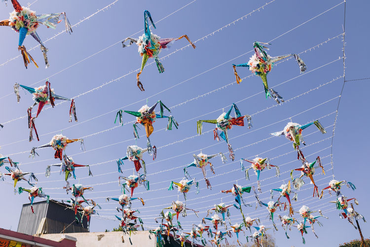 Piñatas against a clear sky hanging between houses in oaxaca, mexico