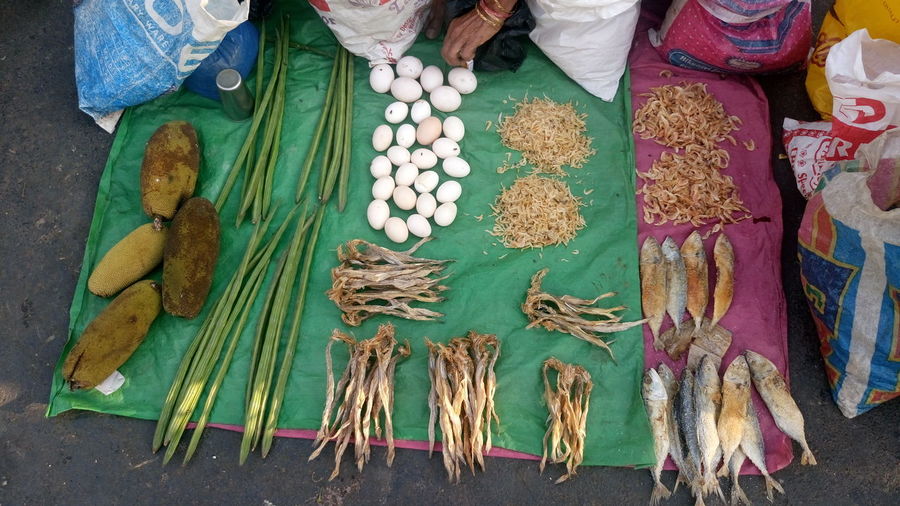 Cropped hand of woman selling dry fish and vegetables at street market