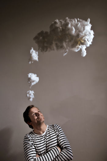 Thoughtful man with cotton in mid-air against gray background