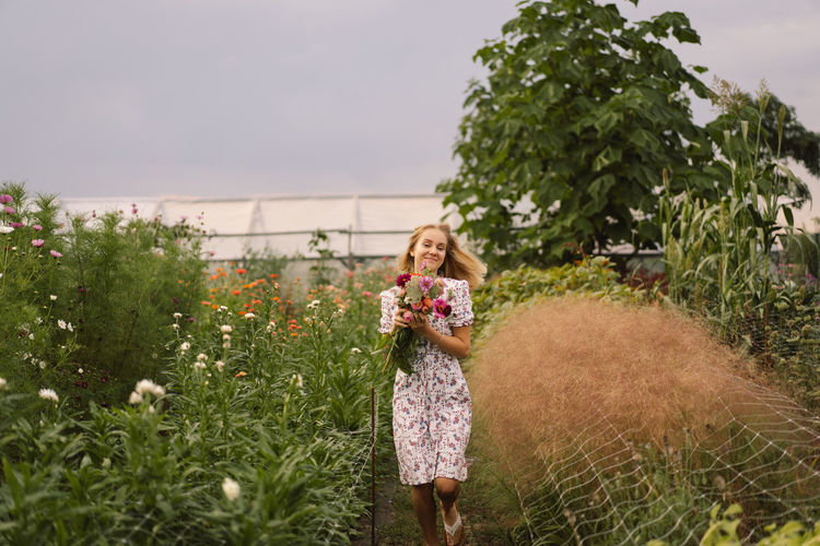 A teenage girl walks with a bouquet of flowers in a floristic flower farm.