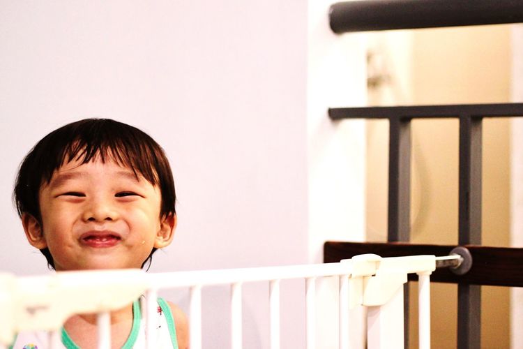 Portrait of smiling boy by railing against wall