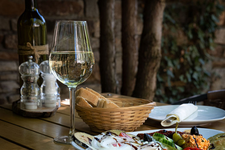 Drinking glass and bread basket on table