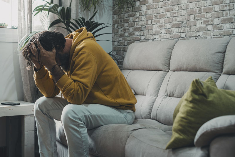 Side view of woman using phone while sitting on sofa at home
