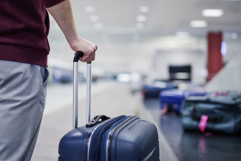 Midsection of man holding suitcase