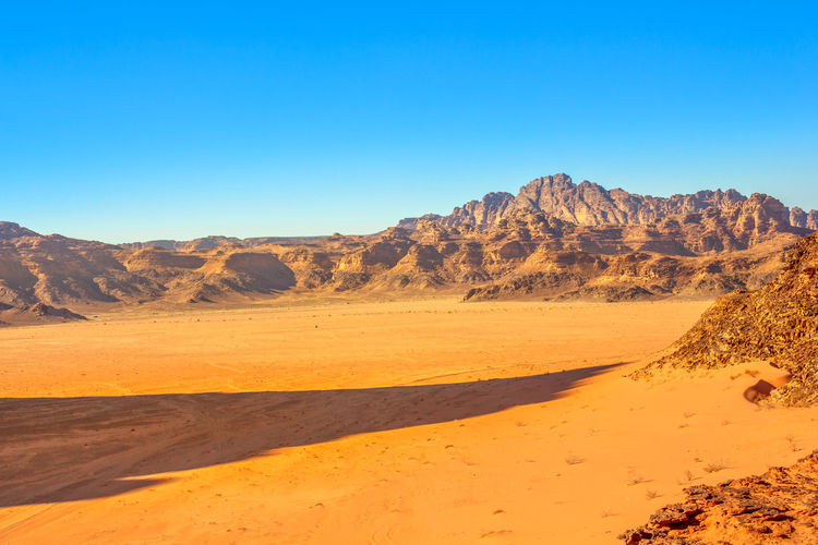 Scenic view of desert against clear blue sky