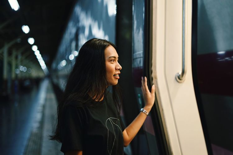 Smiling young woman standing by train at night
