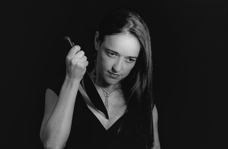 Young woman holding knife against black background