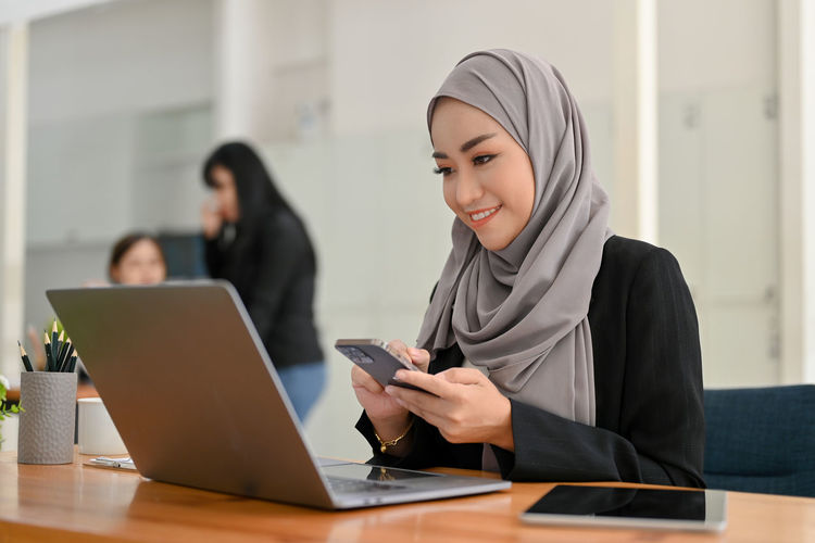 Young woman using digital tablet while sitting in office