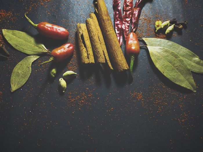 Bay leaves, cinnamon and chili at black background